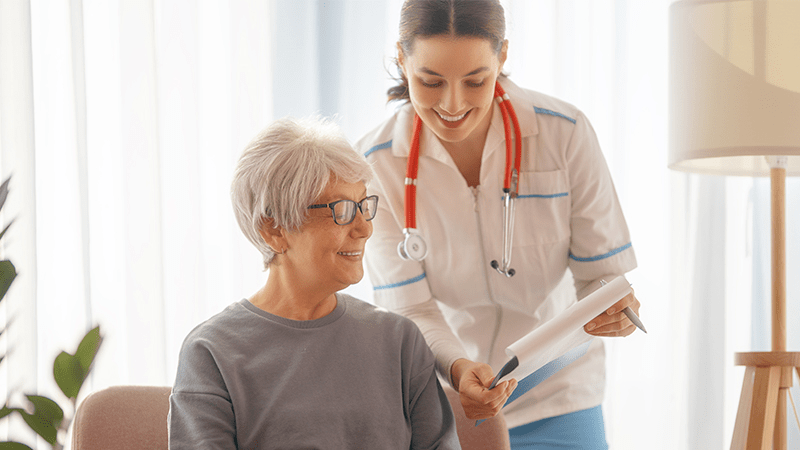 médica e paciente sorrindo com papel na mão