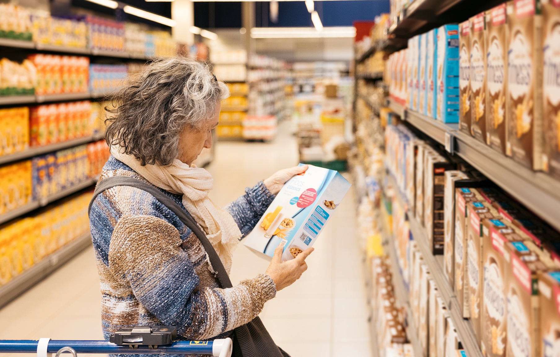 Mulher analisando rótulo de produto alimentício no corredor do supermercado